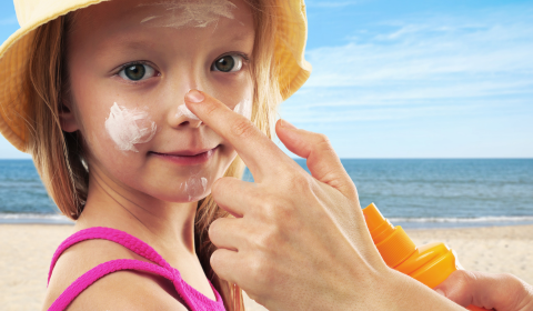 Lapsi rannalla ja kasvoille levitet&auml;&auml;n aurinkovoidetta