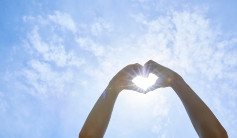 Sormilla tehty syd&auml;nmerkki aurinkoa kohti