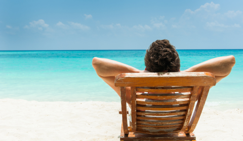 Mies aurinkotuolissa rannalla