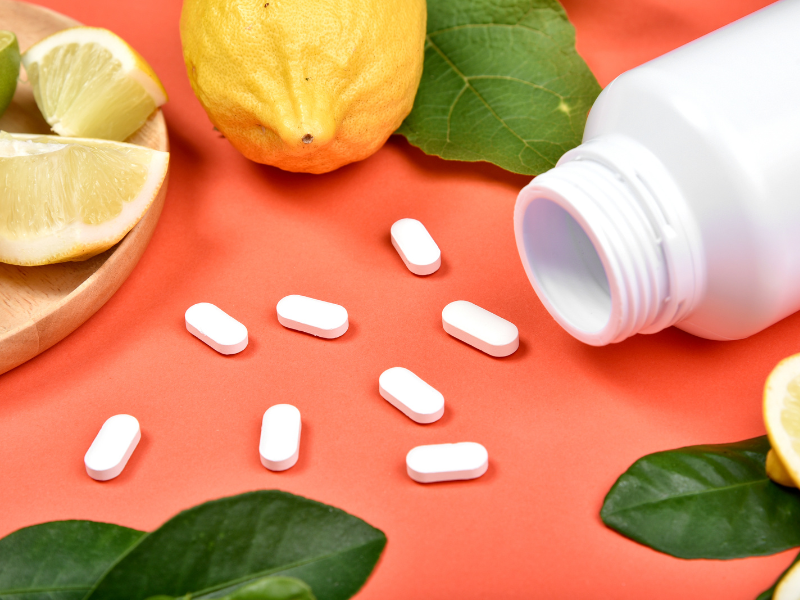 C-vitamiiini tabletteja oranssilla p&ouml;yd&auml;ll&auml; sitruunoiden ymp&auml;r&ouml;im&auml;n&auml;