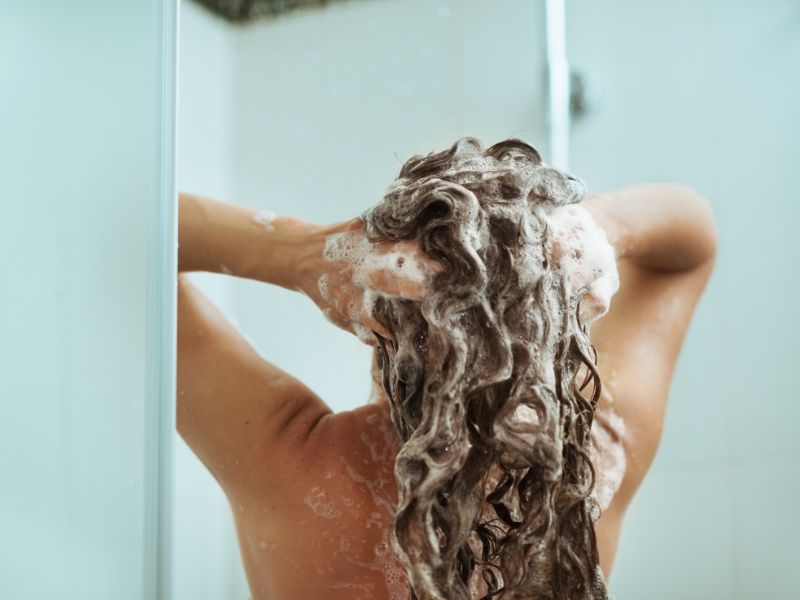 nainen pesee hiuksia suihkussa