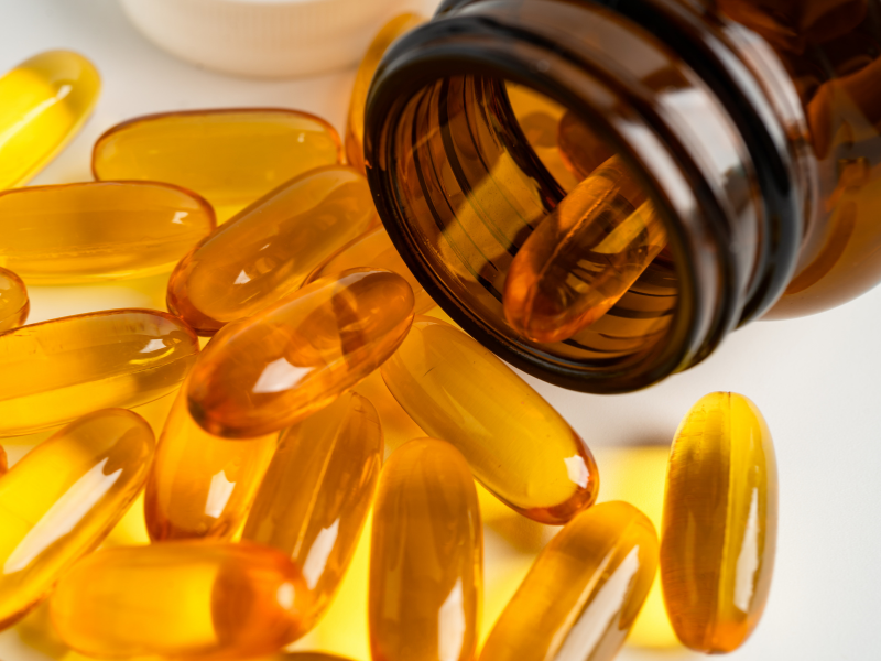 Ruskeasta lasipurkista pursuaa kullankeltaisia &ouml;ljykapseleita