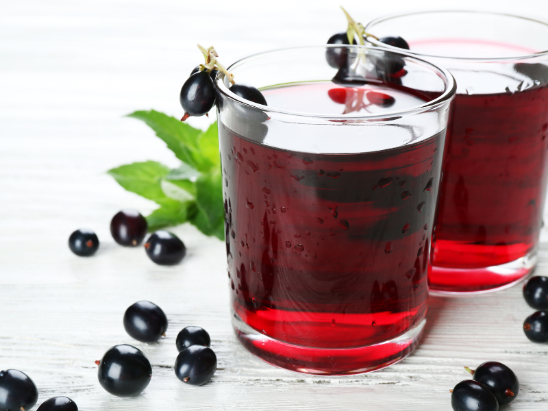 L&auml;mmin musteherukkajuoma lasissa mustaheruokoiden ymp&auml;r&ouml;im&auml;n&auml;